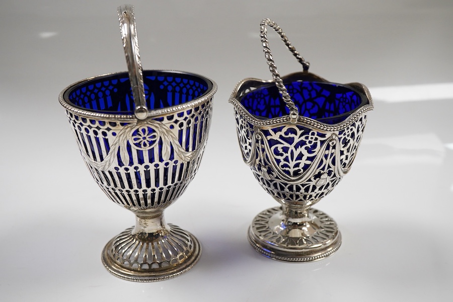 Two George III pierced silver pedestal sugar baskets, with blue glass liners, spiral handle, Burridge Davenport, London, 1777, the other William Plummer, London, 1775, tallest 10.1cm excluding the handle.